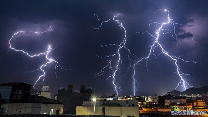 A night sky and flashes of lightning in a small city